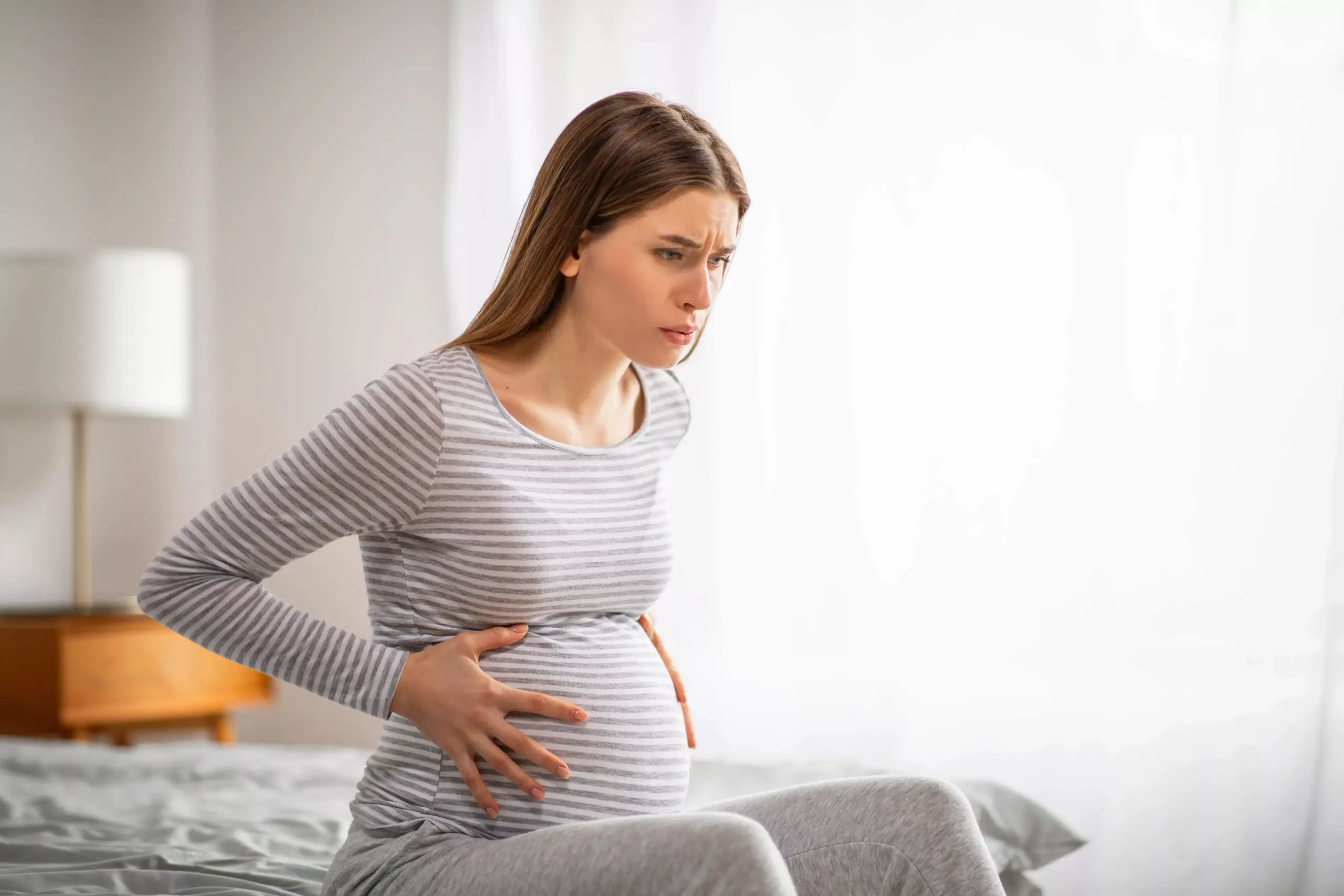 grávida com dores e as mãos na barriga